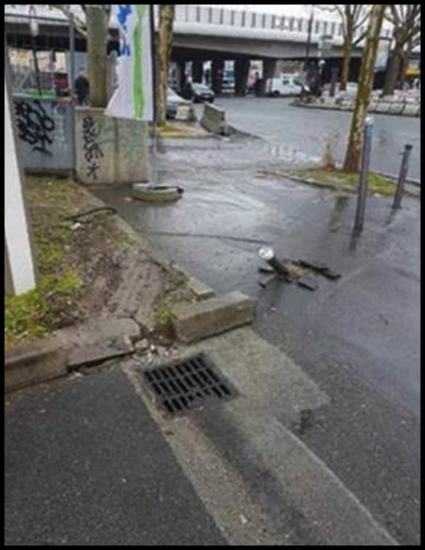 The damaged sidewalk including a broken bollard and broken stone from the sidewalk 