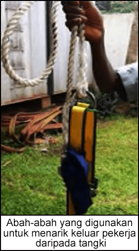 Seorang pekerja sedang memegang abah-abah tali yang digunakan untuk menarik keluar pekerja daripada tangki.