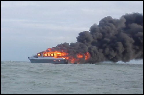 Boat on fire. Large amounts of thick, blank smoke are coming from the vessel. 