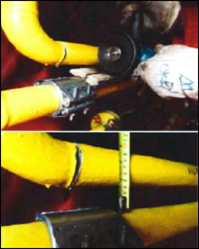 Two yellow nitrogen pipes being cut. A piece of wood is separating the pipes. The clamp is attached to the bottom pipe.