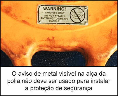 Um sinal de aviso de metal visível no cabo da polia laranja.